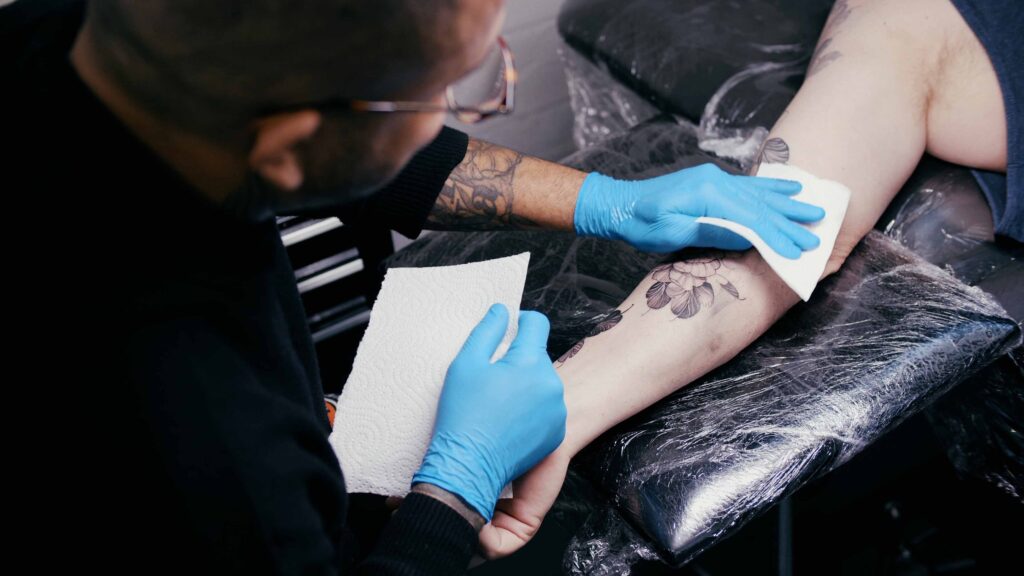 tattoo artist cleaning a floral tattoo.