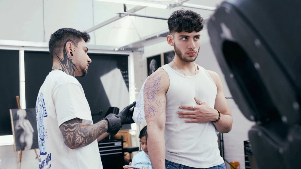 Image of tattoo artist removing stencil from male client's upper arm.
