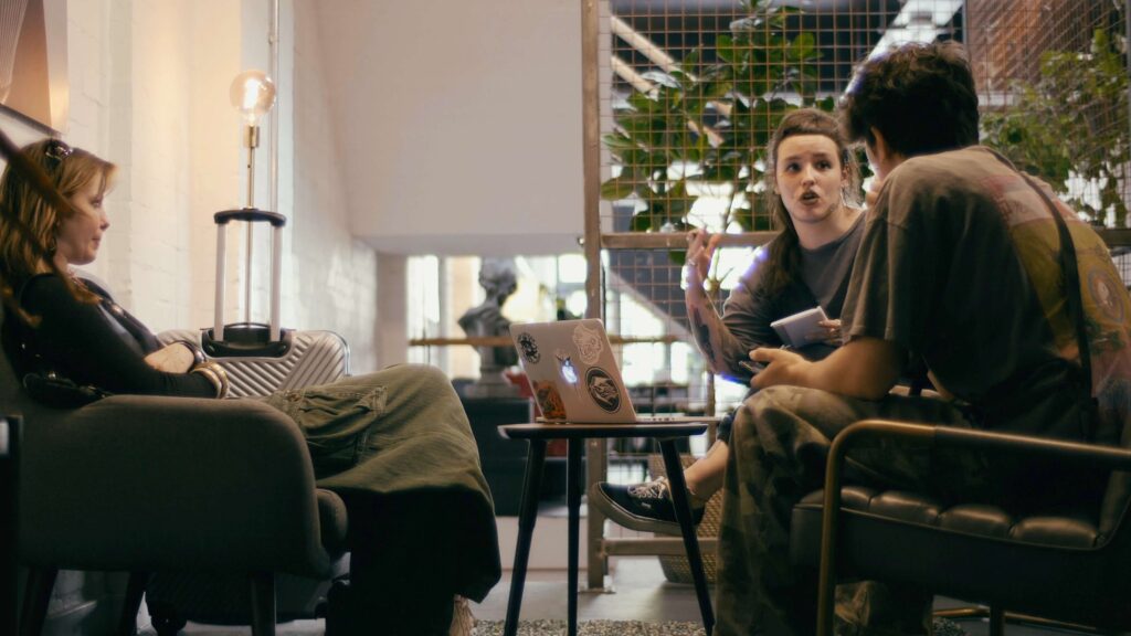 two women and one man sitting on chairs discussing tattoo consultation