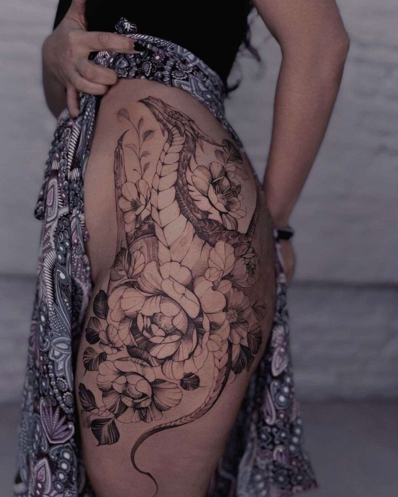 woman holding up her skirt to show a large fineline dragon and floral tattoo on her hip and thigh. 