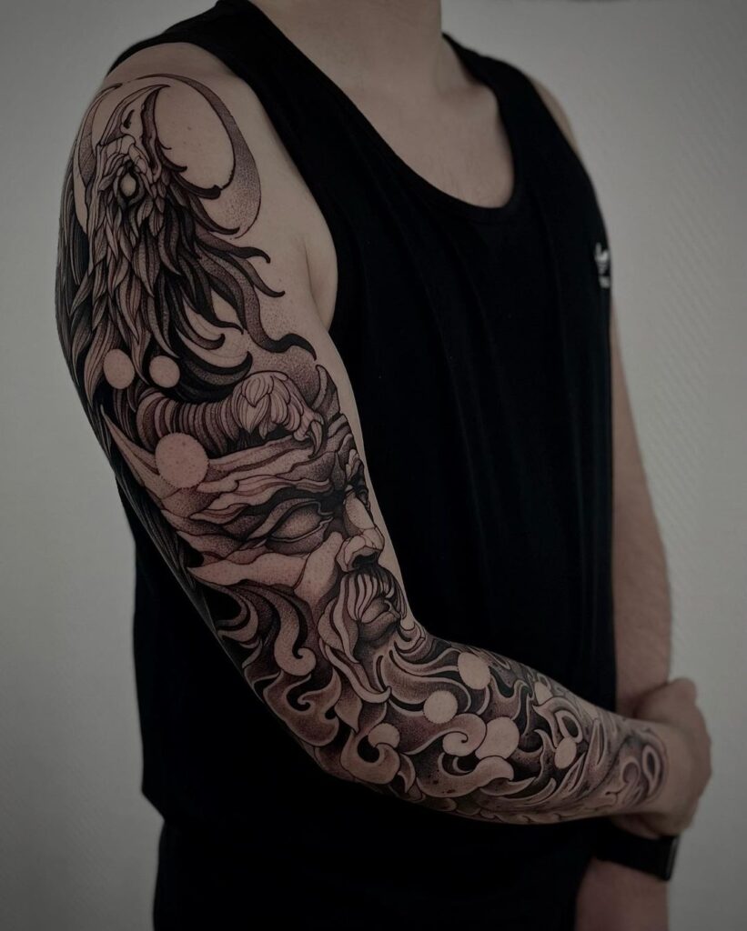 Man in black vest against grey background with Black and grey illustrative tattoo sleeve showing a face and raven with a crescent moon.