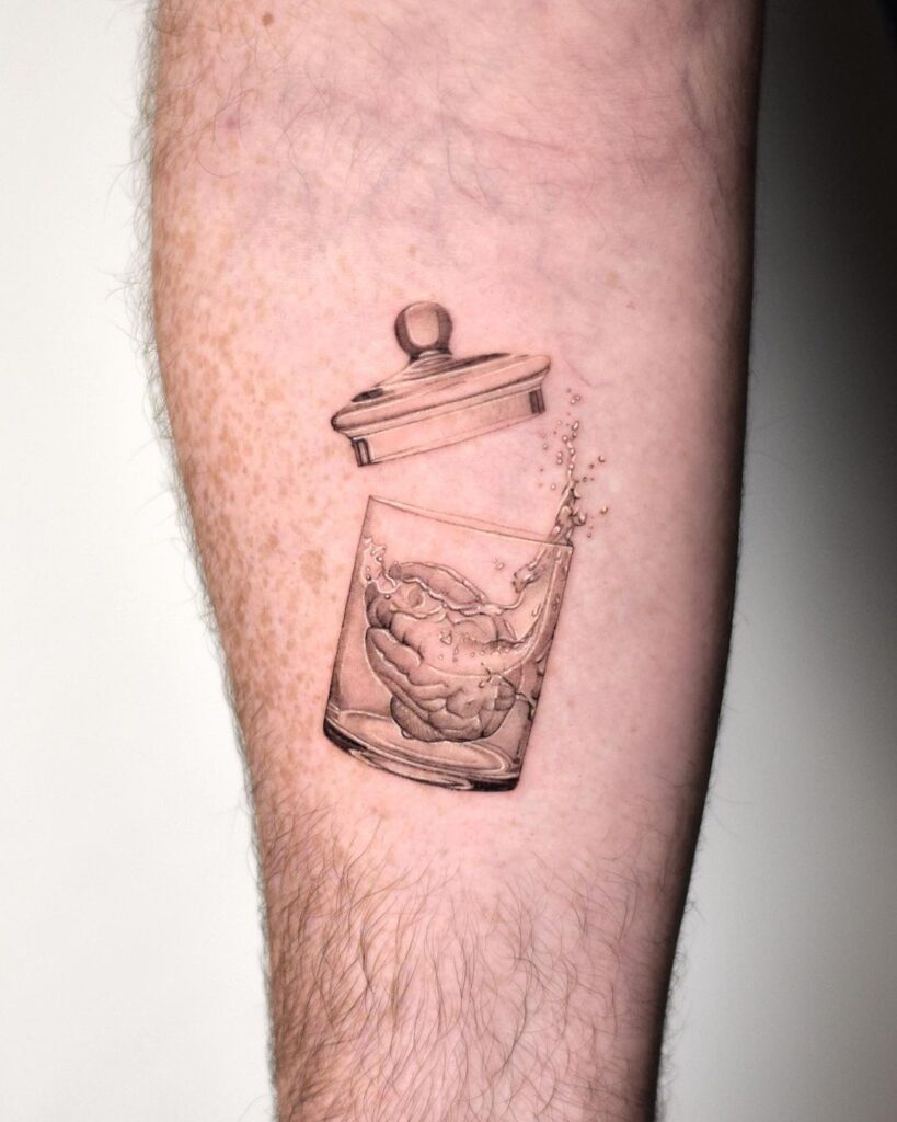 Micro realism black and grey tattoos. Small tattoo of  brain in a glass jar with the lid open and water splashing out of it. 