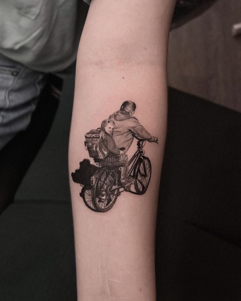Mother's Day tattoos: A black and grey microrealism tattoo of a young girl sitting on the back of a bicycle while her mother pushes it. By Romulo Souza.