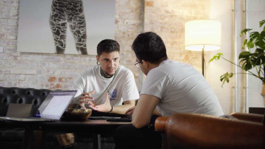Male tattoo artist in deep conversation having a consultation with male client.