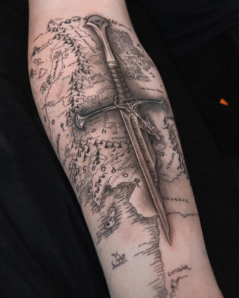 black and grey LOTR tattoo of Aragon's sword on a map of middle earth,